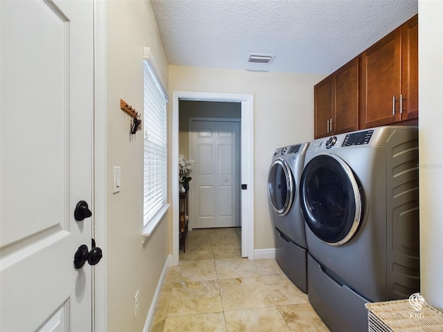 washroom with cabinets, a textured ceiling, separate washer and dryer, and a wealth of natural light