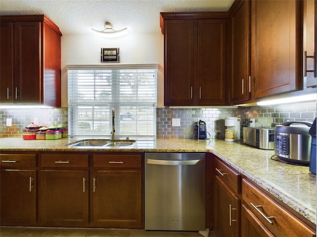 kitchen featuring sink, tasteful backsplash, a textured ceiling, stainless steel dishwasher, and light stone countertops