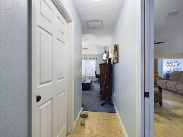 corridor with a textured ceiling and light tile patterned flooring