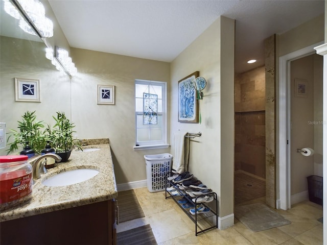 bathroom with tile patterned flooring, vanity, and a tile shower