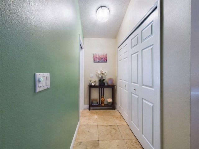 hall with light tile patterned floors and a textured ceiling