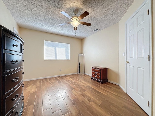 unfurnished bedroom featuring ceiling fan, a textured ceiling, and light wood-type flooring