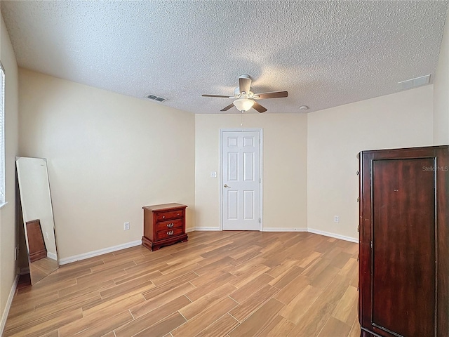 unfurnished bedroom featuring ceiling fan, a textured ceiling, and light hardwood / wood-style flooring