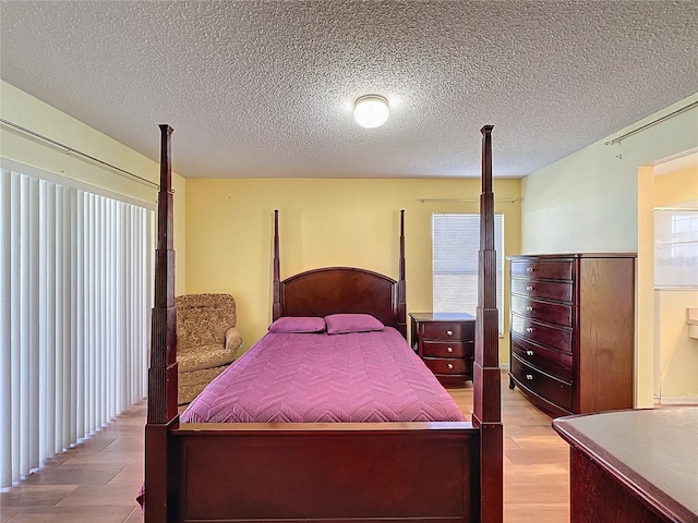 bedroom with light hardwood / wood-style flooring, a textured ceiling, and multiple windows