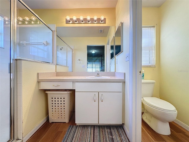 bathroom featuring wood-type flooring, vanity, toilet, and an enclosed shower