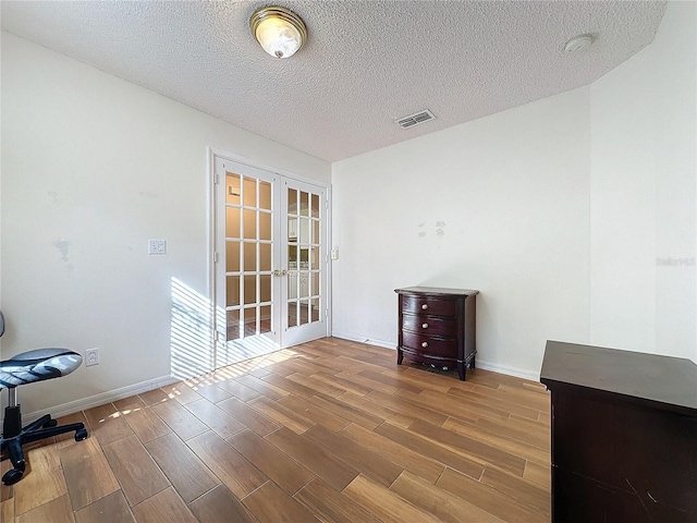 interior space featuring light hardwood / wood-style floors, a textured ceiling, and french doors