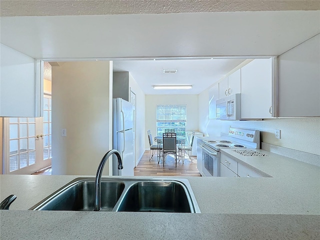 kitchen featuring white cabinetry, white appliances, and sink