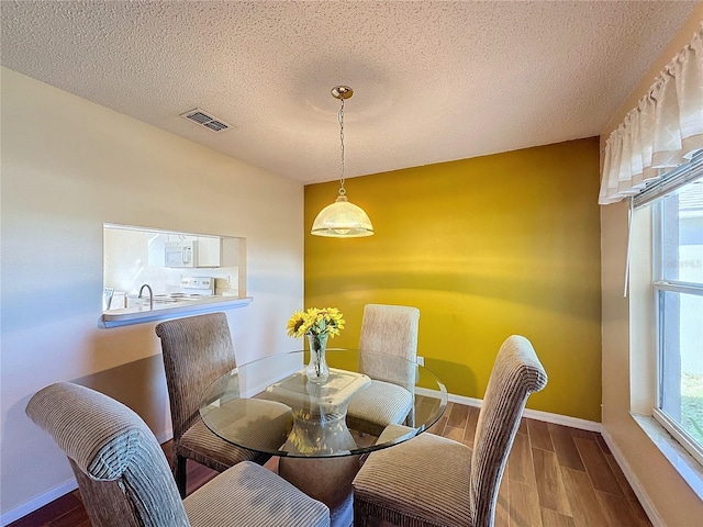 dining space with wood-type flooring and a textured ceiling