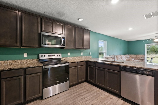 kitchen featuring light stone countertops, light hardwood / wood-style floors, sink, dark brown cabinets, and stainless steel appliances