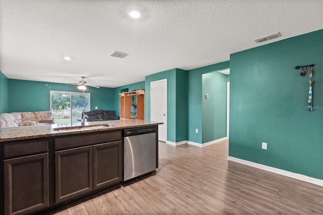 kitchen featuring dark brown cabinets, stainless steel dishwasher, sink, hardwood / wood-style flooring, and a textured ceiling