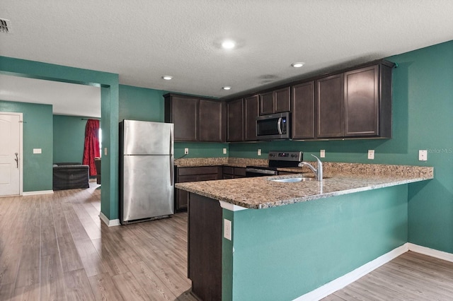 kitchen featuring sink, stainless steel appliances, dark brown cabinetry, and kitchen peninsula