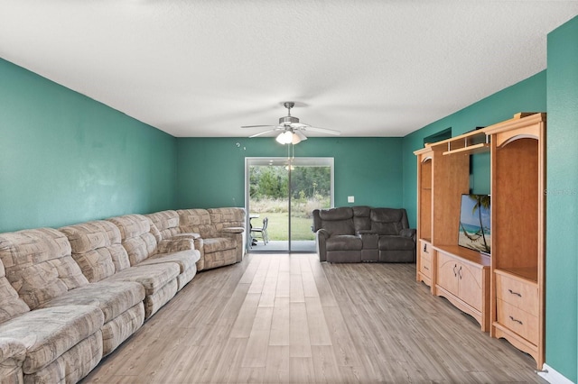 living room featuring light wood-type flooring, ceiling fan, and a textured ceiling