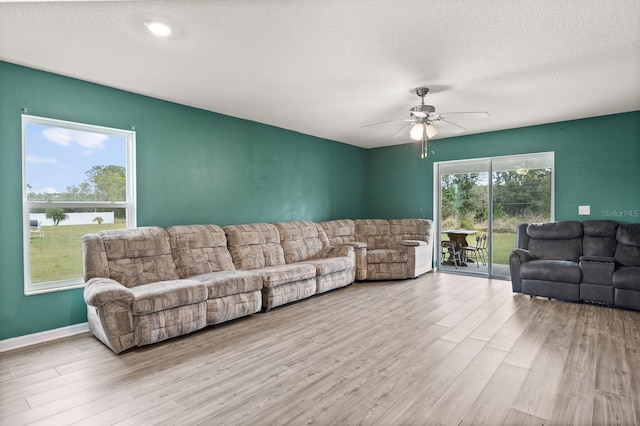 living room with ceiling fan, light hardwood / wood-style floors, and a textured ceiling