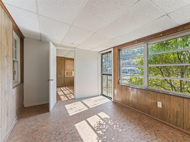 empty room with wood walls and a drop ceiling