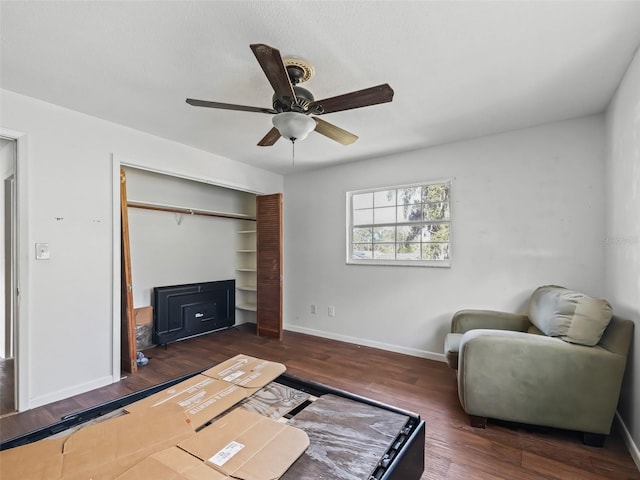 sitting room featuring dark wood-type flooring and ceiling fan