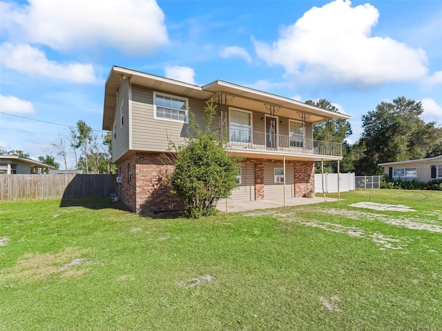 rear view of house with a balcony, a patio, and a yard