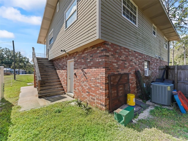 view of property exterior with central AC unit and a lawn