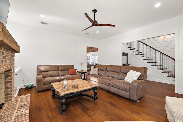 living room featuring ceiling fan, dark wood-type flooring, and a brick fireplace