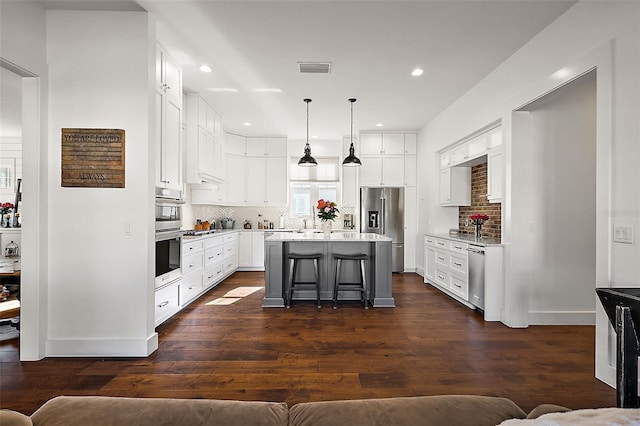 kitchen featuring white cabinetry, hanging light fixtures, high end fridge, a breakfast bar, and a kitchen island