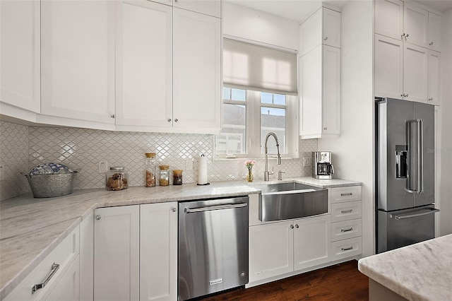 kitchen featuring light stone countertops, sink, decorative backsplash, white cabinets, and appliances with stainless steel finishes