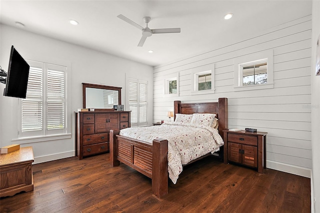 bedroom with dark hardwood / wood-style floors, ceiling fan, and wood walls