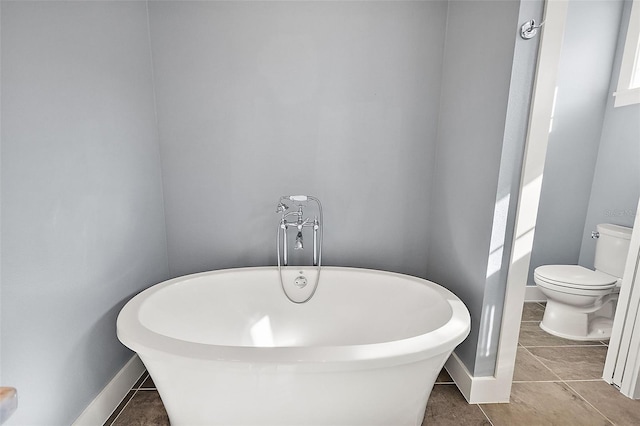 bathroom featuring tile patterned floors, toilet, and a bath