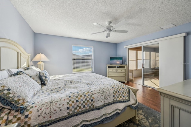 bedroom with ceiling fan, dark hardwood / wood-style floors, a textured ceiling, and a closet