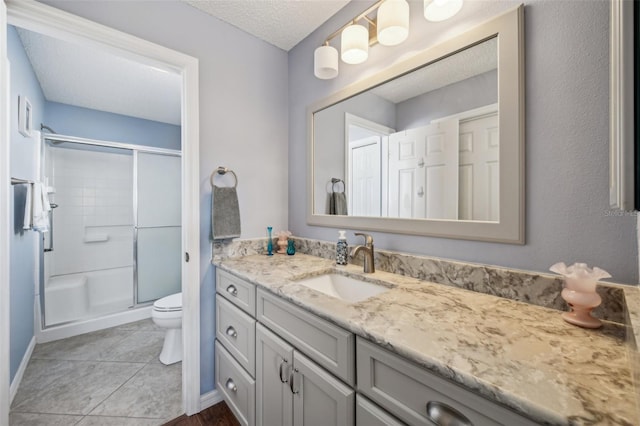 bathroom with tile patterned floors, a textured ceiling, vanity, a shower with door, and toilet