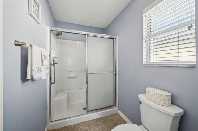 bathroom with toilet, tile patterned flooring, plenty of natural light, and walk in shower