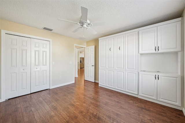 unfurnished bedroom with ceiling fan, dark hardwood / wood-style floors, and a textured ceiling