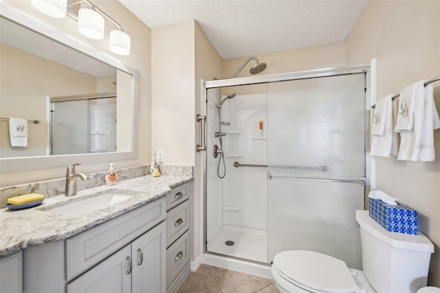 bathroom featuring tile patterned floors, a textured ceiling, toilet, vanity, and a shower with shower door