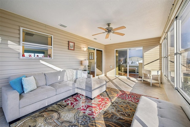 living room featuring ceiling fan, light tile patterned floors, and a textured ceiling