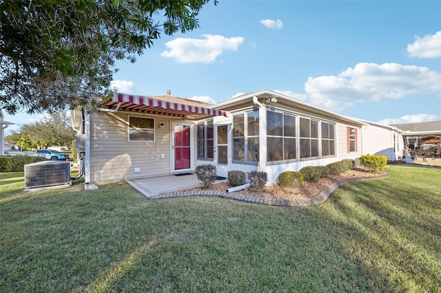 rear view of property featuring central air condition unit, a patio area, a sunroom, and a yard