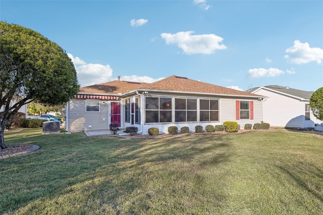 view of front of house with a patio area, a sunroom, a front yard, and central AC