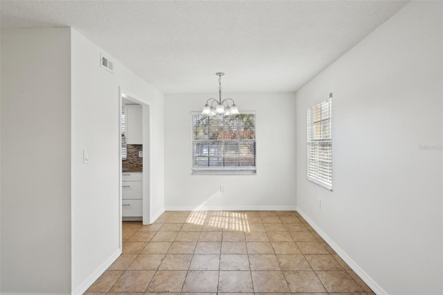 unfurnished dining area featuring light tile patterned flooring, a textured ceiling, and an inviting chandelier