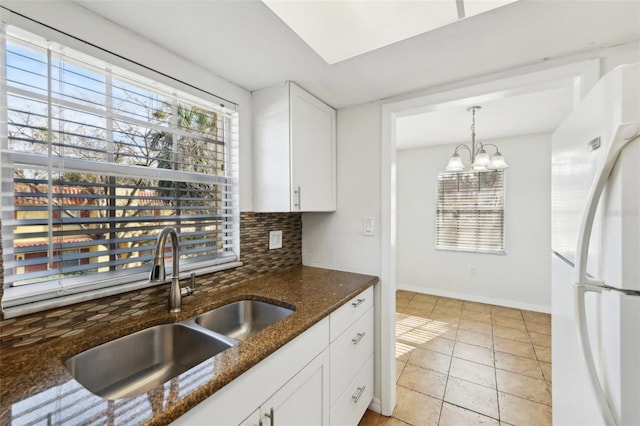 kitchen featuring white cabinetry, sink, white refrigerator, backsplash, and dark stone counters