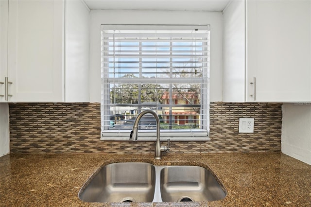 kitchen featuring white cabinets, tasteful backsplash, dark stone countertops, and sink