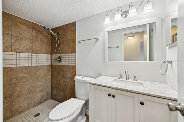 bathroom featuring tiled shower, a textured ceiling, vanity, and toilet