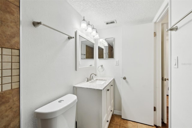 bathroom featuring tile patterned flooring, vanity, a textured ceiling, and toilet