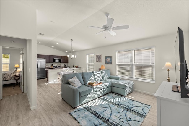 living room featuring ceiling fan with notable chandelier, light wood-type flooring, and vaulted ceiling