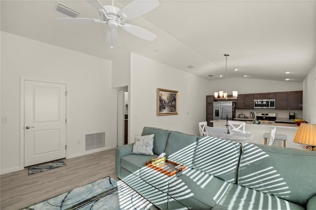 living room featuring ceiling fan, light hardwood / wood-style floors, sink, and vaulted ceiling