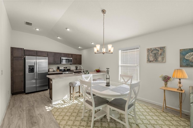 dining room featuring sink, a chandelier, vaulted ceiling, and light hardwood / wood-style flooring