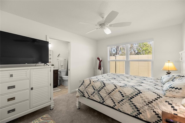 bedroom with light colored carpet, ceiling fan, and ensuite bathroom