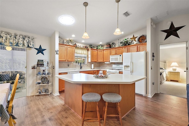 kitchen featuring lofted ceiling, a center island, white appliances, and light hardwood / wood-style flooring