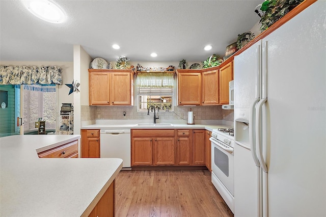 kitchen with white appliances, light hardwood / wood-style floors, backsplash, and sink