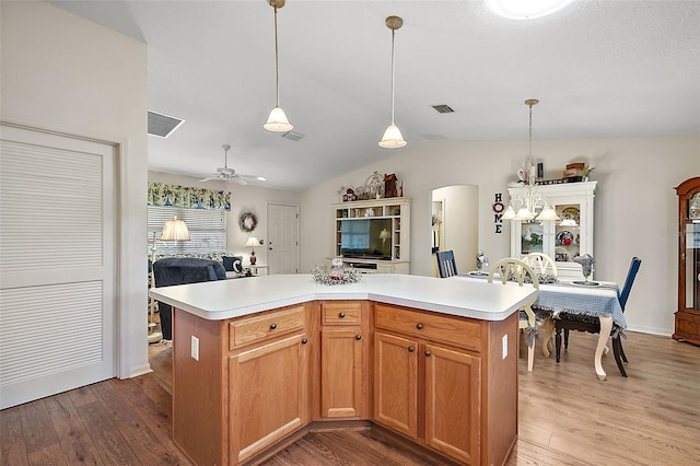 kitchen with decorative light fixtures, a kitchen island, ceiling fan, and light hardwood / wood-style flooring