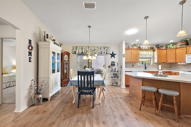 dining area with sink, light hardwood / wood-style floors, and an inviting chandelier