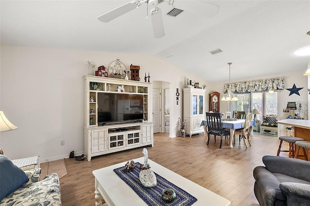 living room with ceiling fan with notable chandelier, hardwood / wood-style flooring, and lofted ceiling