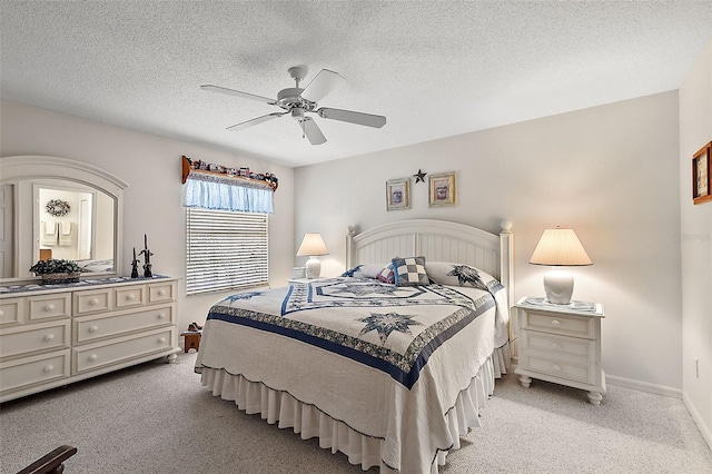 bedroom with ceiling fan, light colored carpet, and a textured ceiling