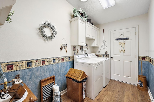 washroom with light hardwood / wood-style floors, cabinets, a textured ceiling, and washing machine and clothes dryer